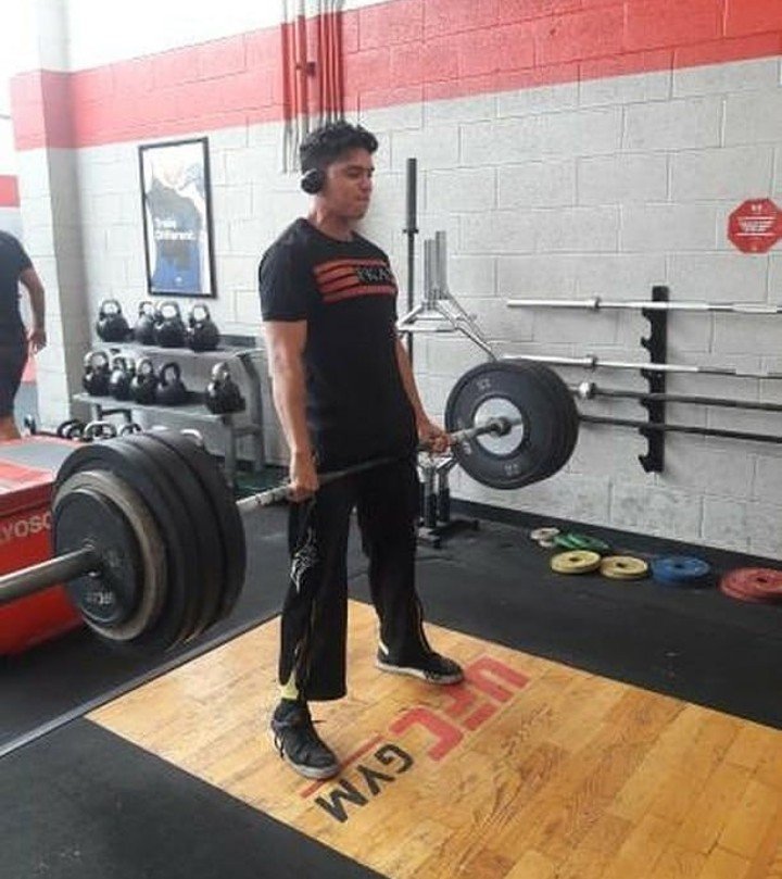 Coach Carlos deadlifting a loaded barbell at UFC Gym